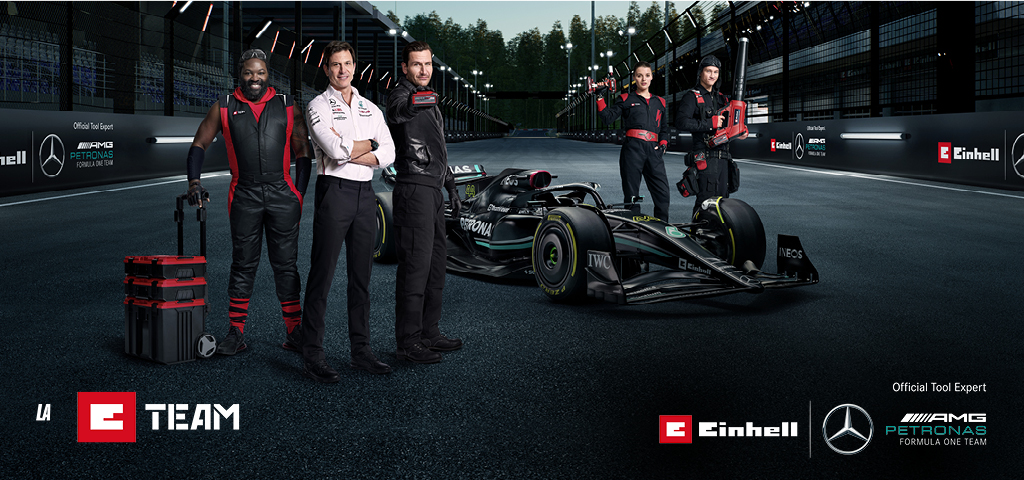 The E-Team on a race track in front of the Mercedes-AMG PETRONAS F1 racing car.