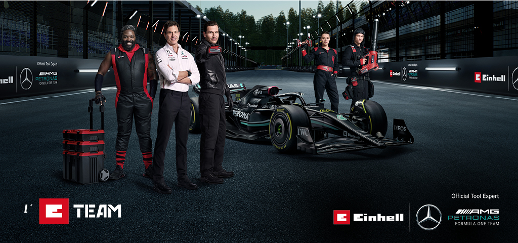 The E-Team on a race track in front of the Mercedes-AMG PETRONAS F1 racing car.