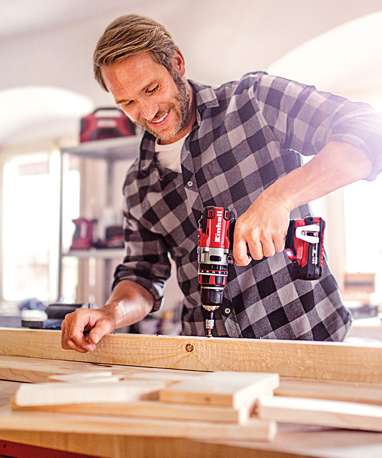 A picture of a man screwing a screw into a piece of wood with an Einhell Cordless Screwdriver.