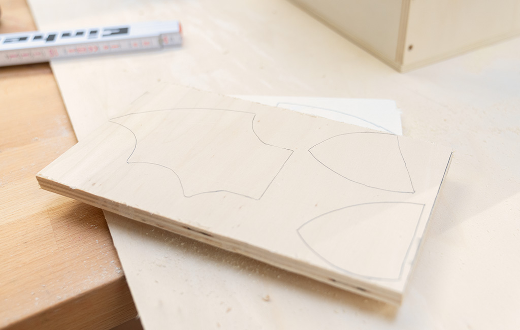 Ein Holzbrett, auf dem mehrere geschwungene Formen gezeichnet sind, bereit zum Zuschneiden.