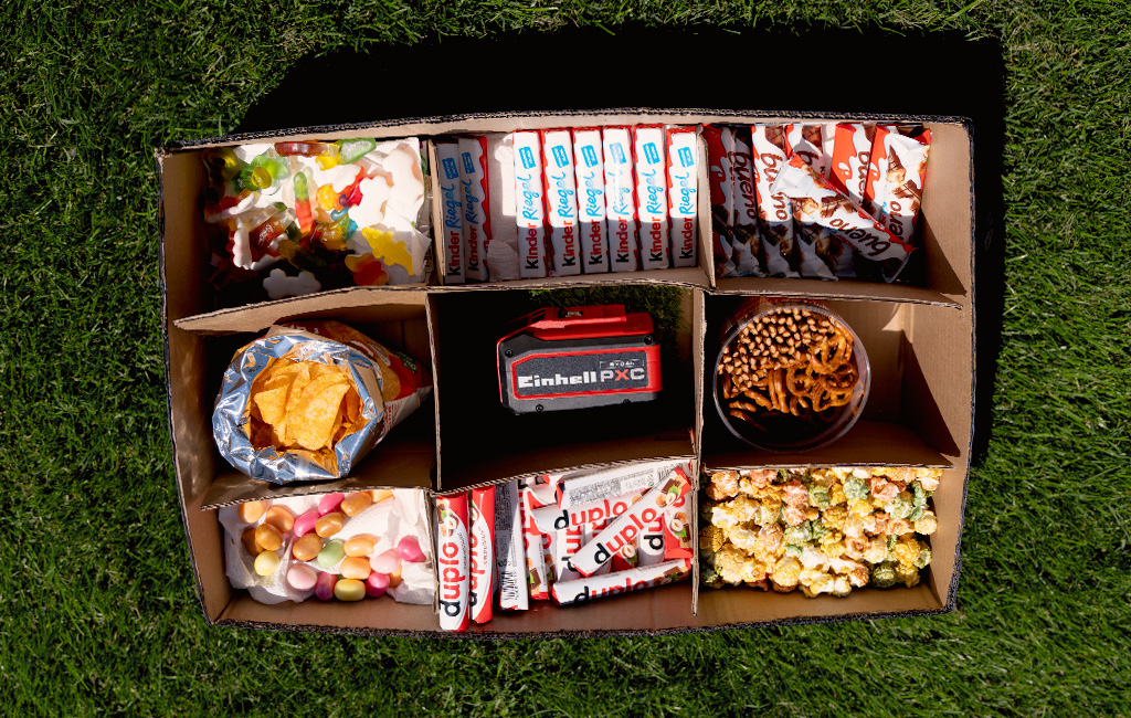 Draufsicht auf Snackbox mit Süßigkeiten, Chips und Brezeln in mehreren Fächern.