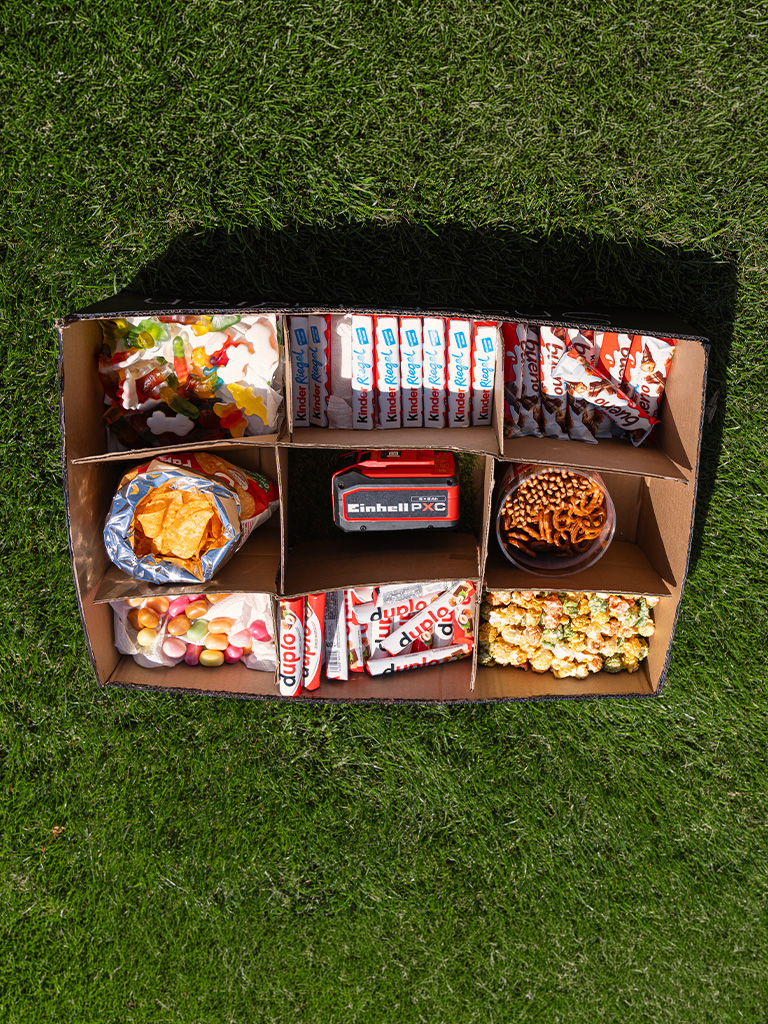 Draufsicht auf Snackbox mit Süßigkeiten, Chips und Brezeln in mehreren Fächern.
