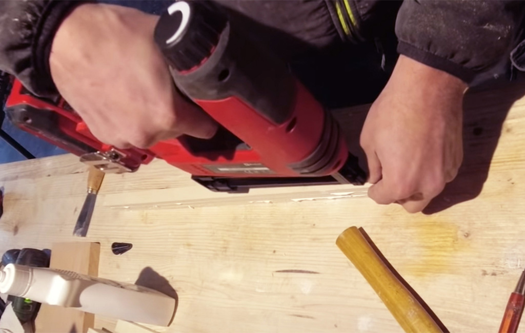 Man attaches wooden slats using a cordless stapler on a workbench.