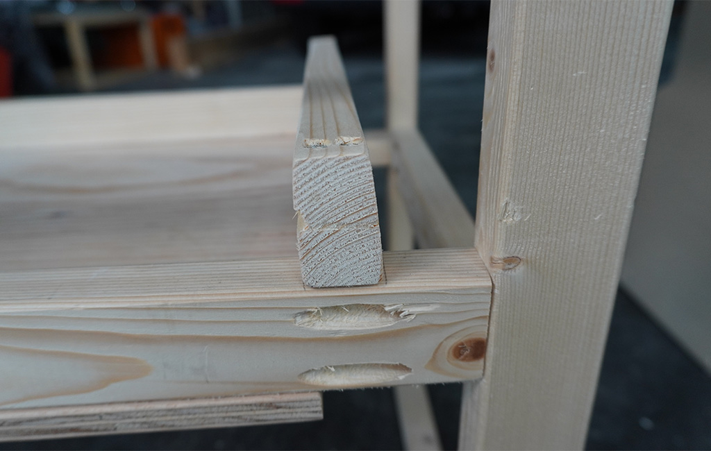Close-up of a wooden frame with an inserted shelf and pocket hole joints.