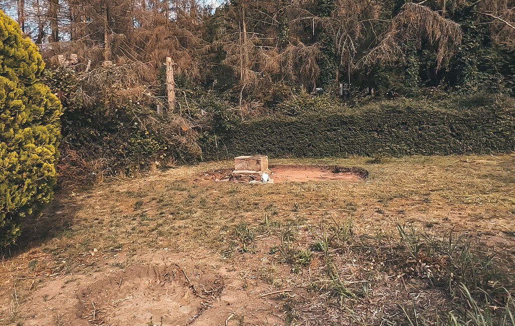 Eine freie Rasenfläche mit einer kleinen, alten Betonplatte in der Mitte.