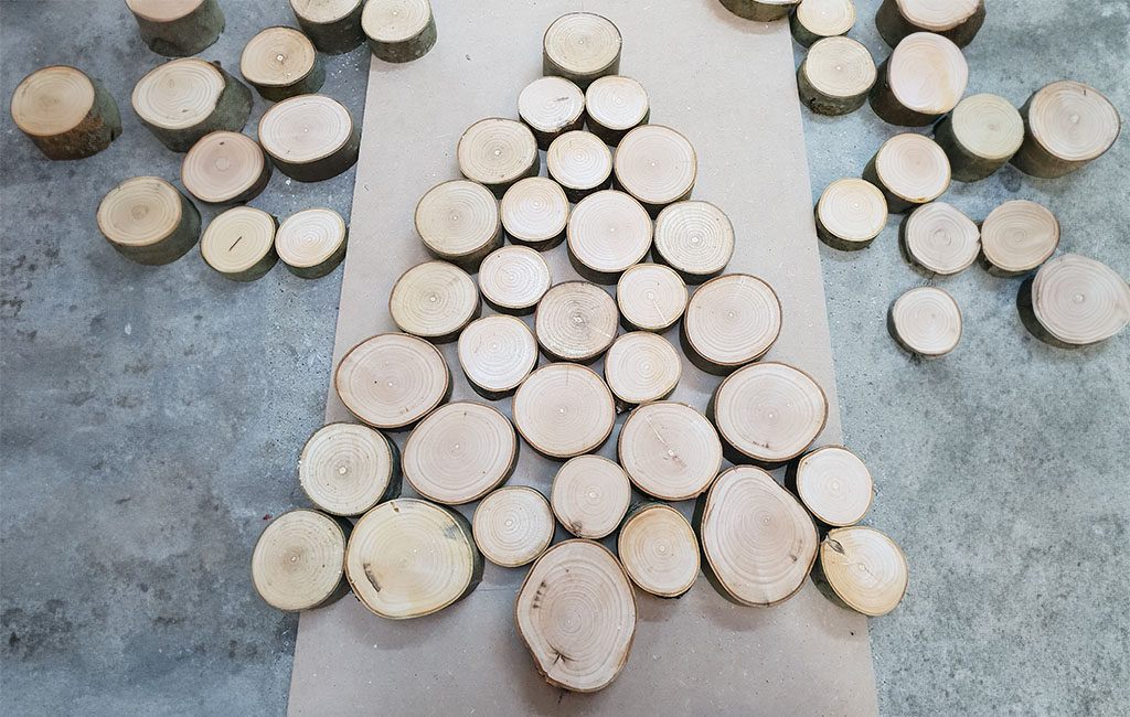Wooden discs are arranged on the floor in the shape of a Christmas tree.