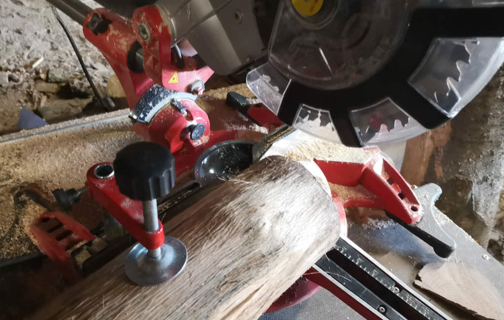 Holzstamm wird mit einer Gehrungssäge als Teil eines DIY-Weihnachtsdeko-Projekts geschnitten.