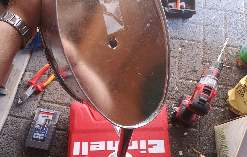 Ein rundes Metallteil mit großem Bohrloch in der Mitte, daneben liegt ein Einhell Akkuschrauber.