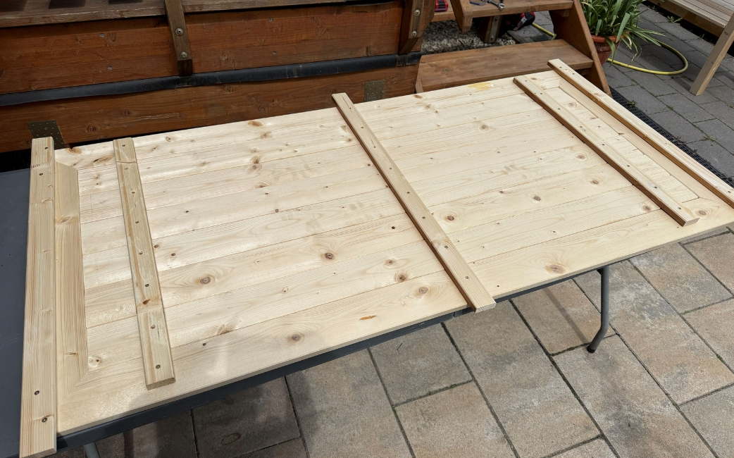 Eine fertig montierte Rückwand für den Pflanztisch liegt mit sichtbaren Leisten auf der Rückseite.