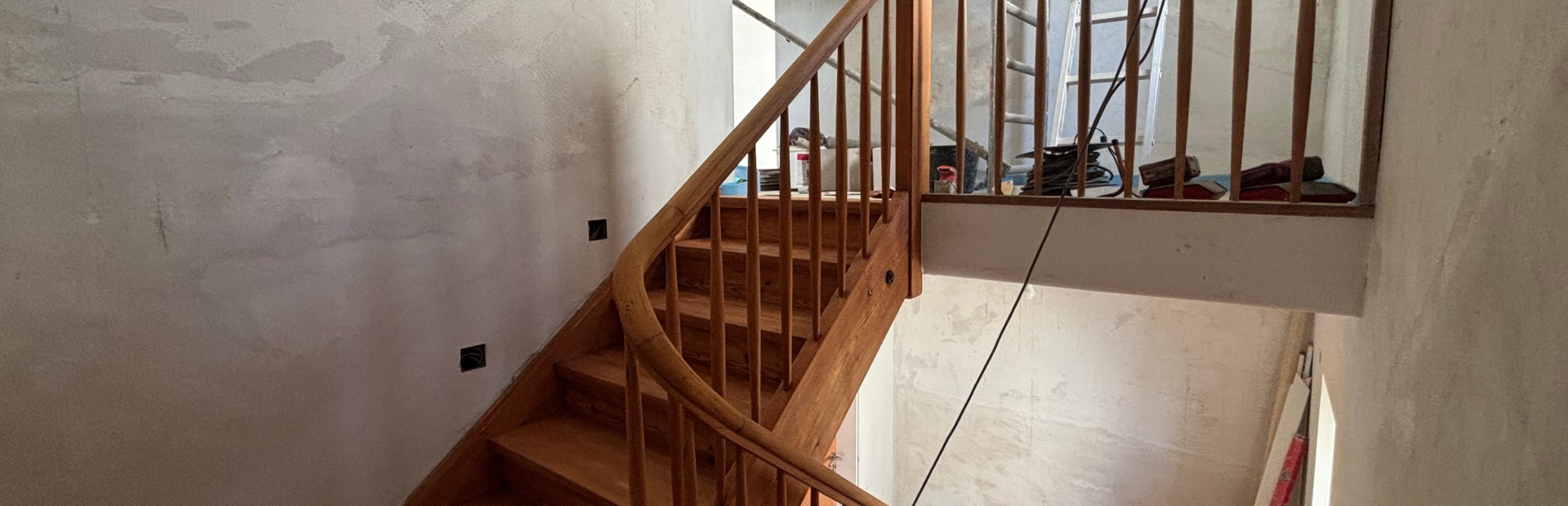 Geschliffene Holztreppe mit Geländer im Innenbereich während der Renovierung.