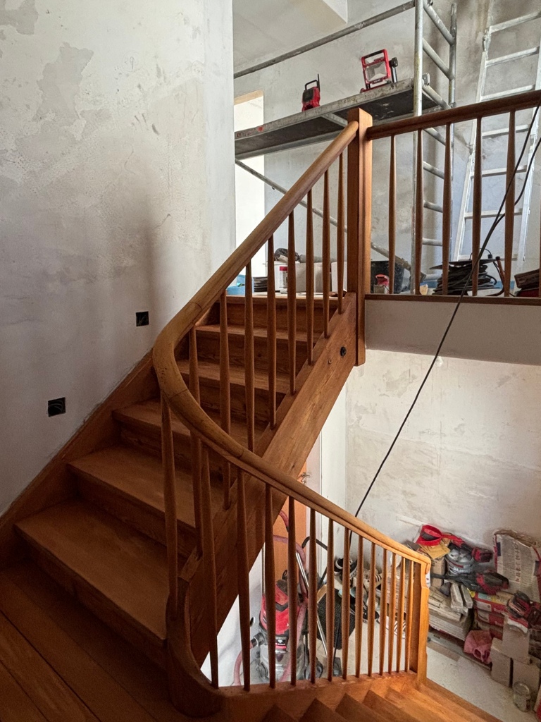 Geschliffene Holztreppe mit Geländer im Innenbereich während der Renovierung.