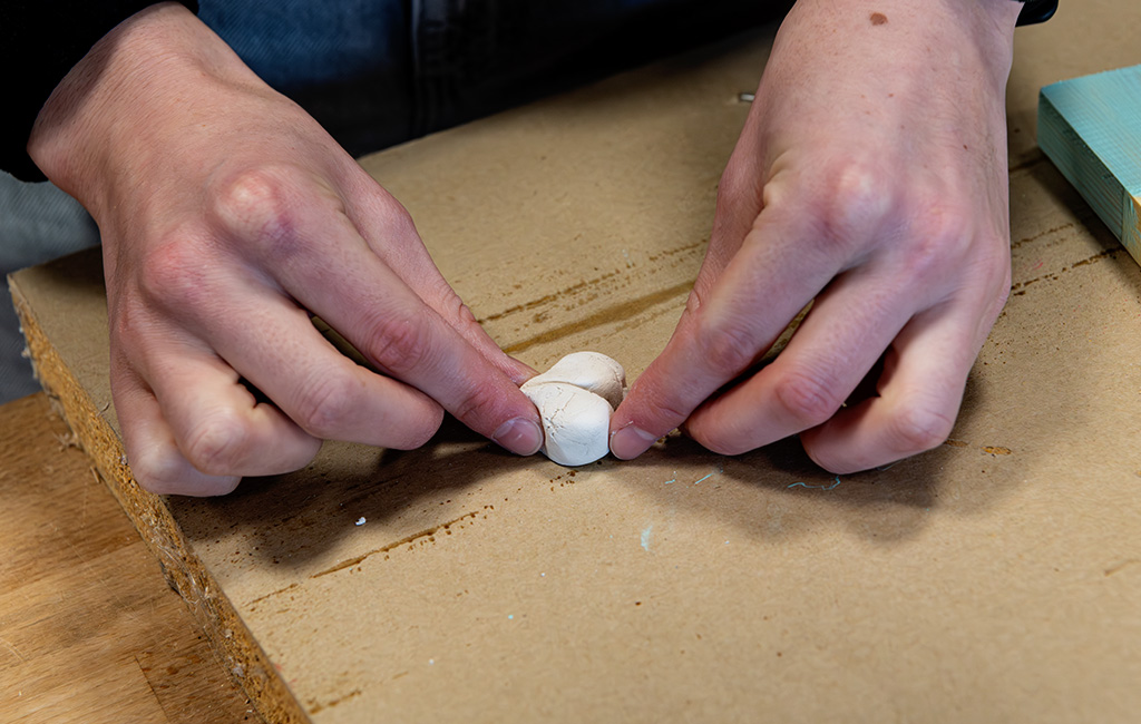 Zwei Hände formen aus weißer Modelliermasse ein kleines Herz.