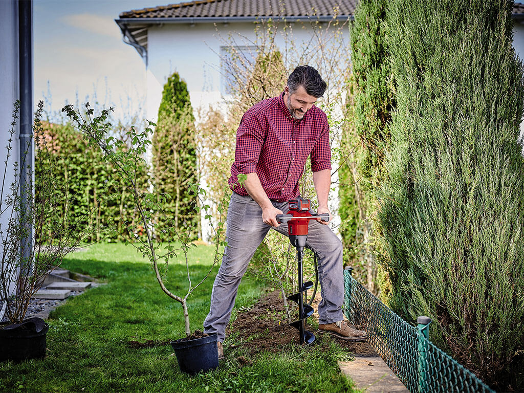 a man drills a hole with the earth drill