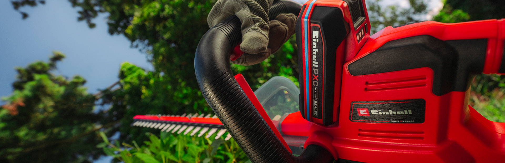 Einhell-Akku-Heckenschere schneidet eine Hecke im Garten.