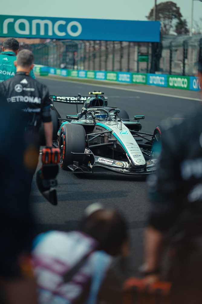 Voiture F1 Mercedes dans la voie des stands entourée de l’équipe