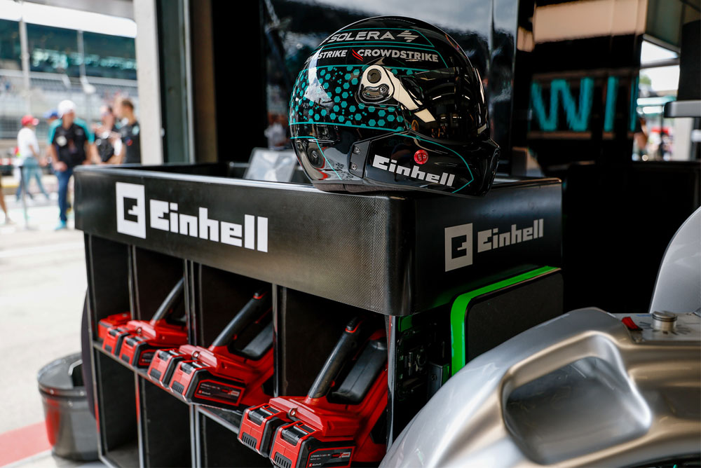 Outils sans fil Einhell dans un chariot roulant, avec un casque de course posé dessus.