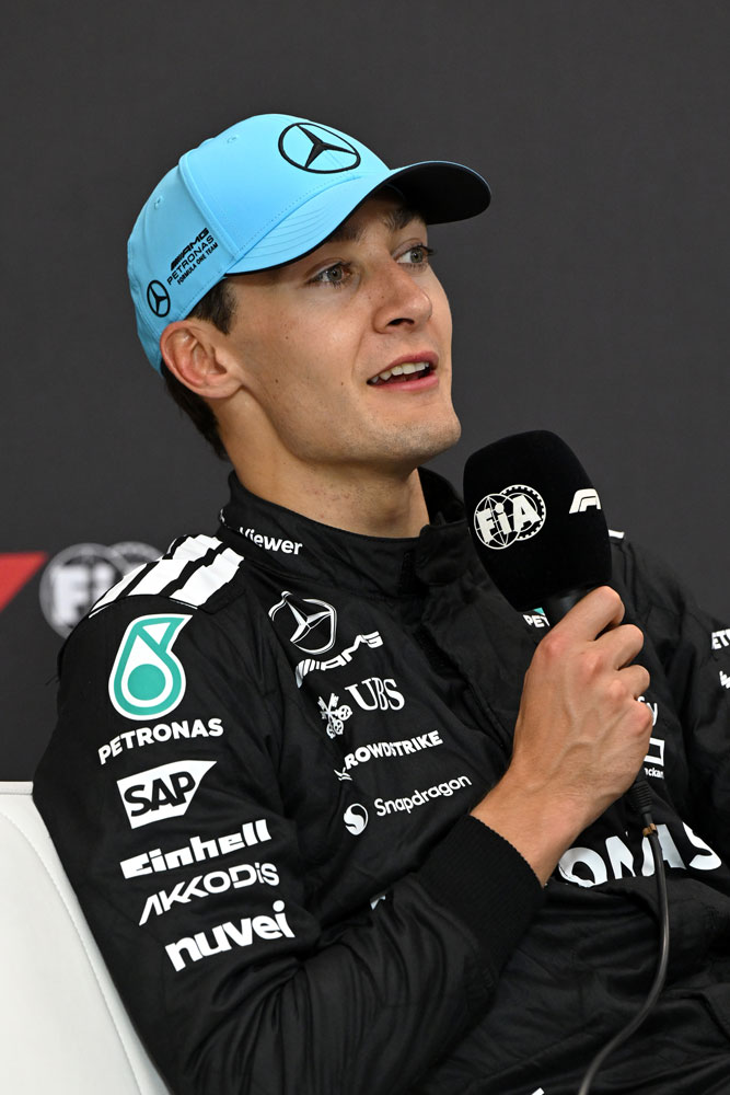 Le pilote de Formule 1 George Russell avec un microphone dans la main droite.