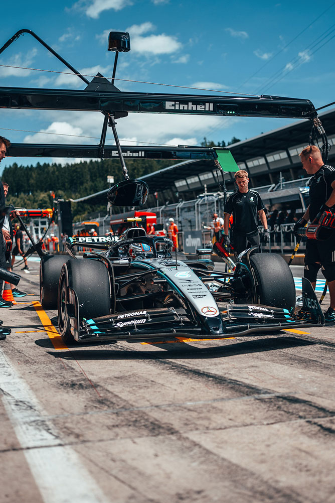 Une voiture de Formule 1 Mercedes-AMG se trouve dans la voie des stands, entourée de membres de l’équipe sous une structure de garage Einhell.