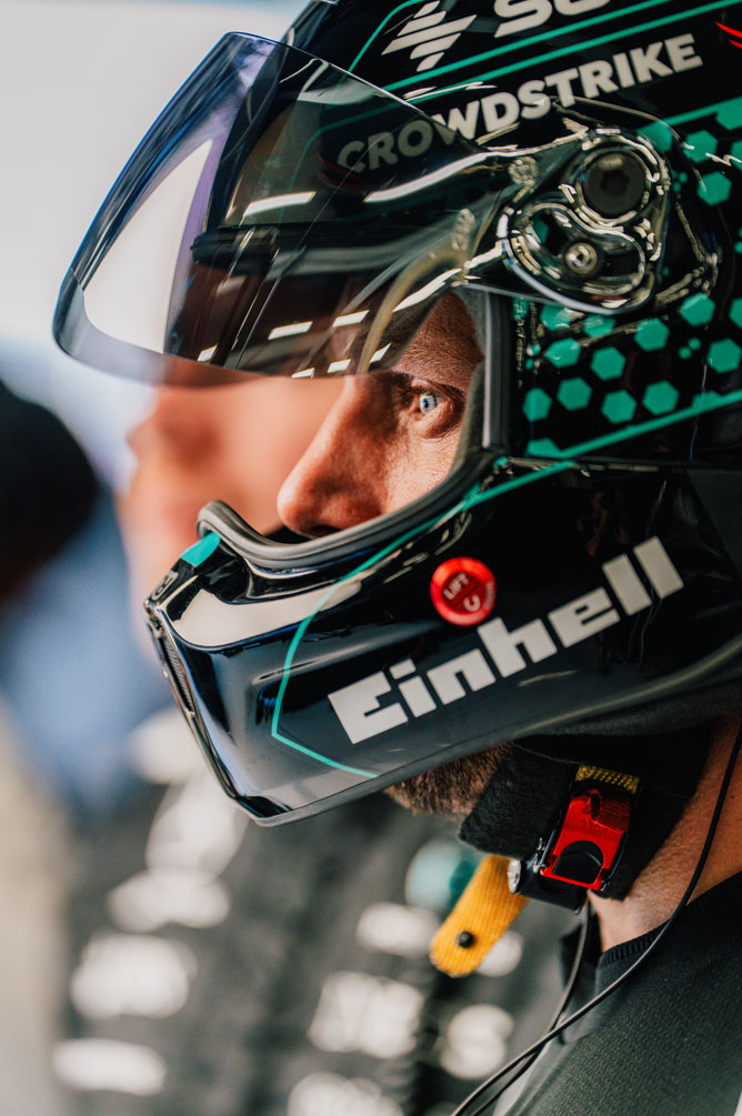 Un membre de l’équipe de Formule 1 porte un casque et regarde sur le côté avec concentration.