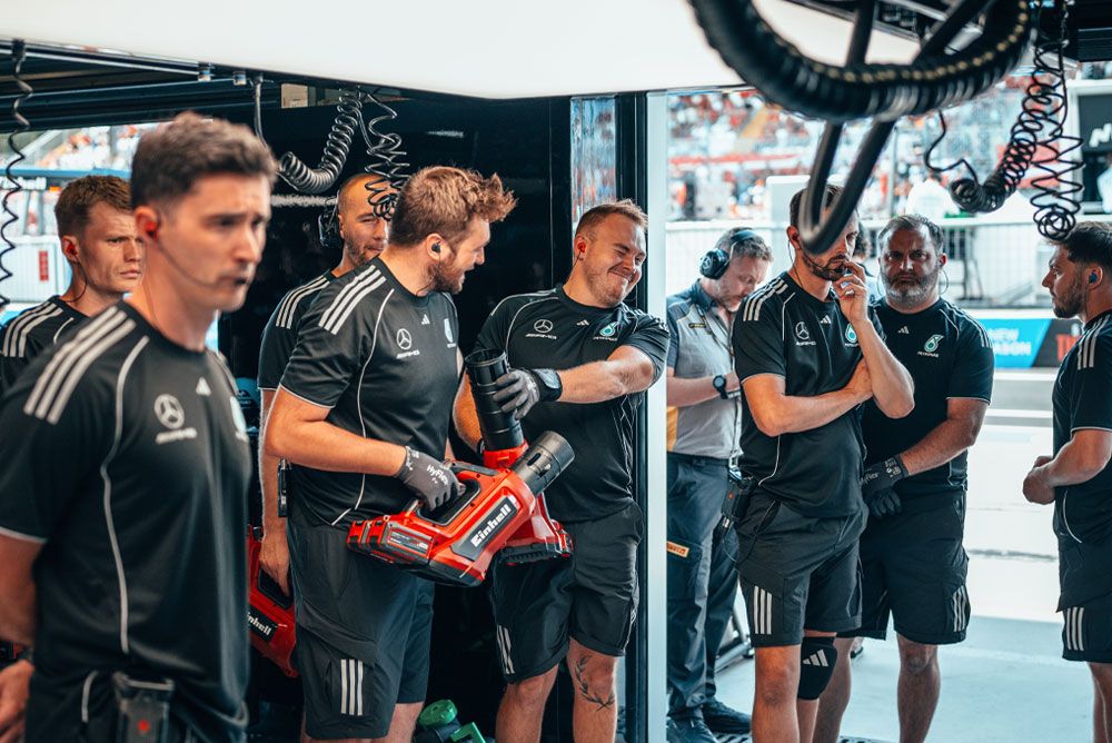 Il team Mercedes-AMG PETRONAS di Formula 1 si trova nel box. Due membri del team tengono in mano soffiatori a batteria rossi di Einhell, pronti per la prossima operazione.