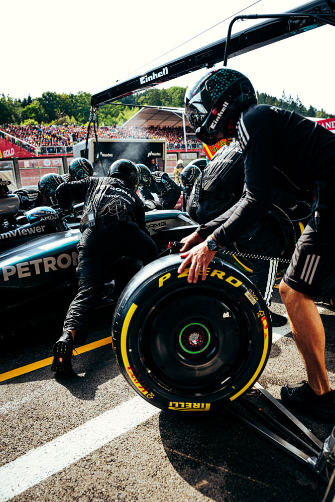 I meccanici del team Mercedes-AMG PETRONAS Formula One eseguono un pit stop. Un membro del team sta preparando uno pneumatico Pirelli mentre altri lavorano sull'auto. Il marchio Einhell è visibile sull'attrezzatura sopra la vettura.