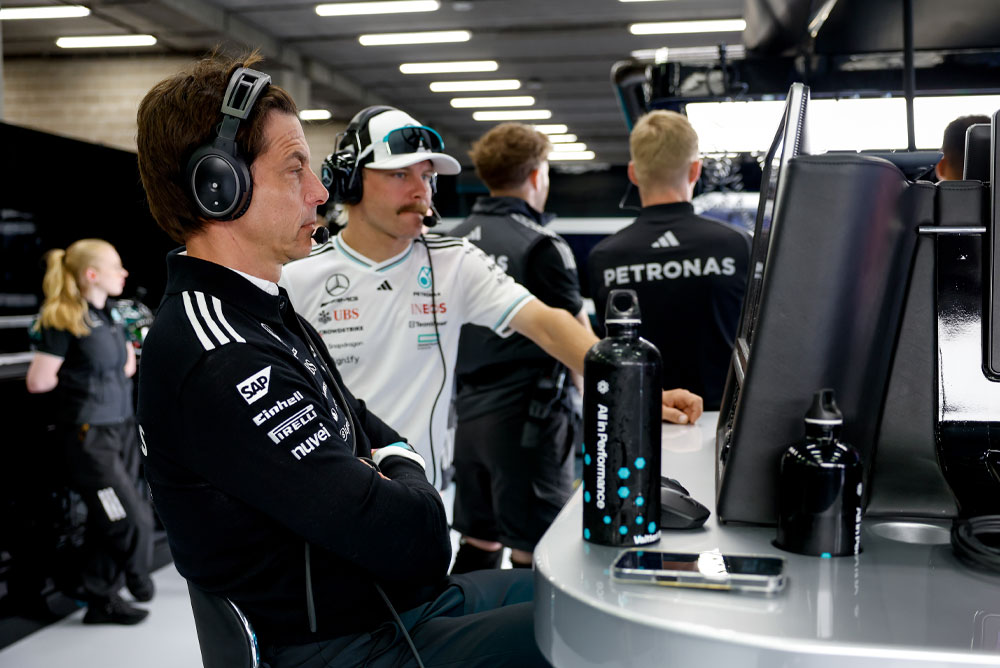 Toto Wolff e Valtteri Bottas del team Mercedes-AMG PETRONAS Formula One sono alla postazione del team nel garage. Sono concentrati sulla strategia di gara, osservano i monitor e comunicano tramite cuffie.