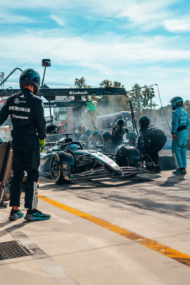 Un pit stop ad alta intensità per il team Mercedes-AMG PETRONAS di Formula 1. La squadra è all’opera, cambiando le gomme e controllando la vettura sotto il ponte con il marchio Einhell.