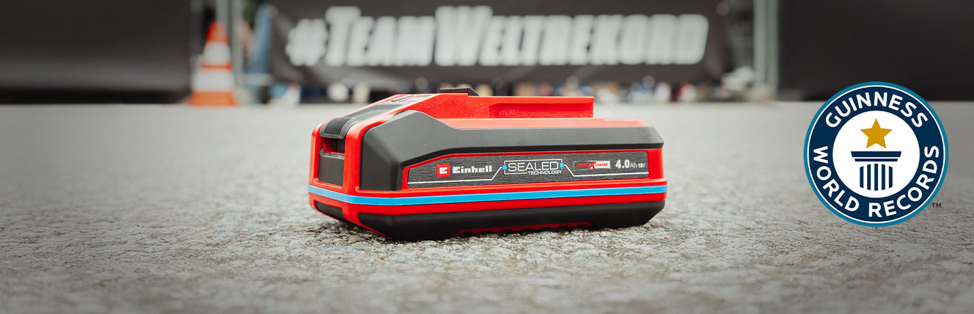 Einhell SEALED Akku Power X-Change 4,0 Ah liegt auf Asphalt, rechts das Guinness World Records-Logo.