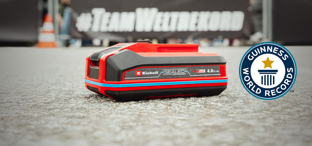 Einhell SEALED Akku Power X-Change 4,0 Ah liegt auf Asphalt, rechts das Guinness World Records-Logo.