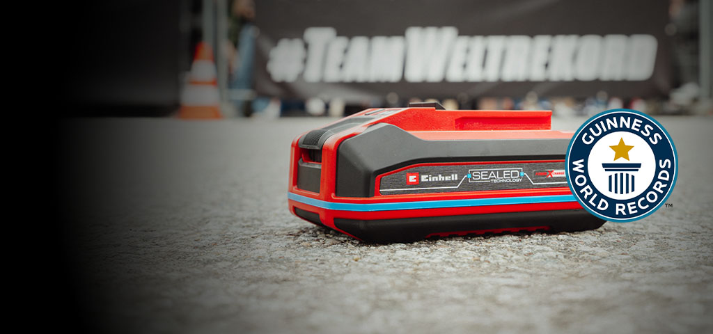 Batteria Einhell SEALED Power X-Change 4.0 Ah posata sull’asfalto, con il logo Guinness World Records «Record Holder» a destra.