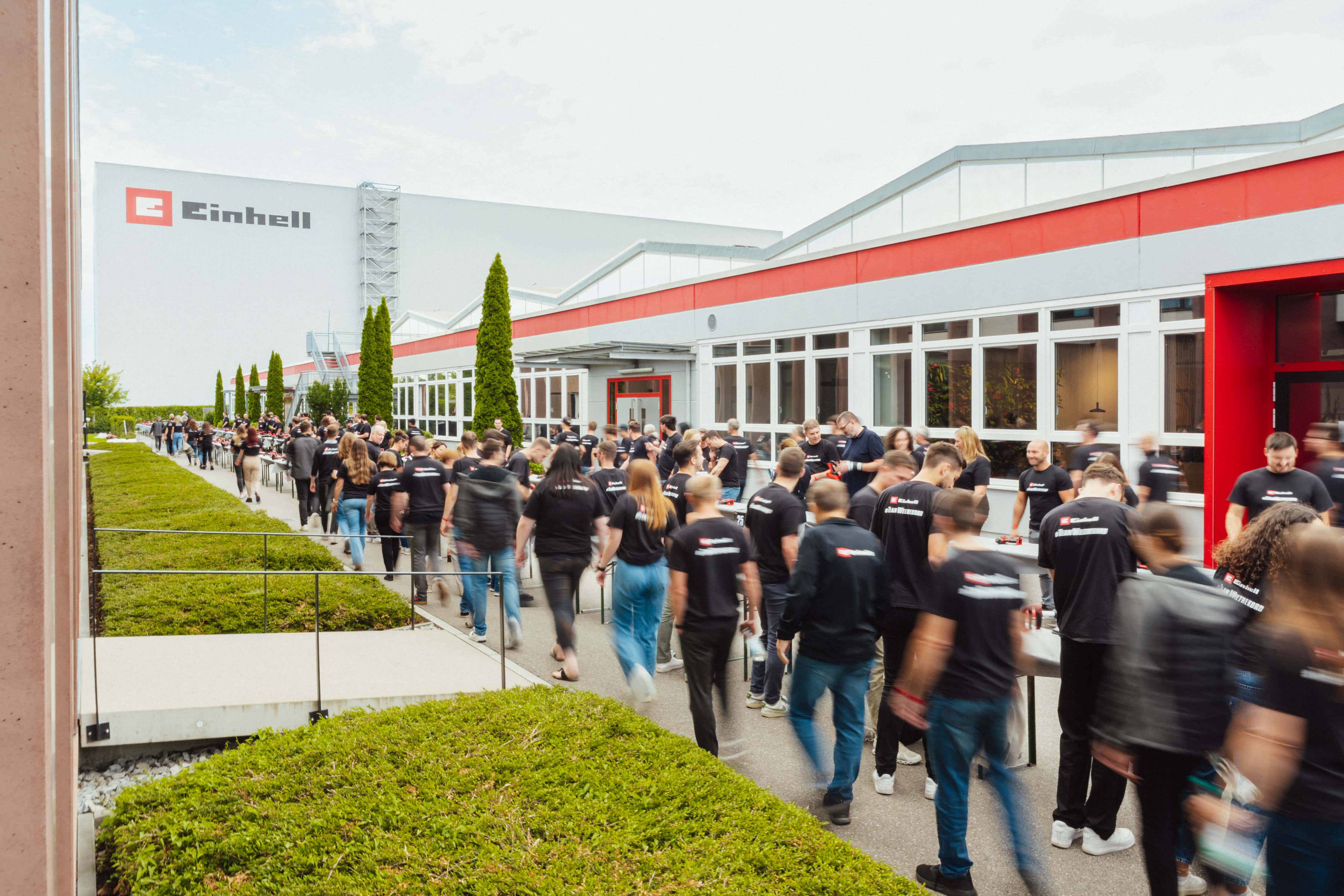 Menschenkette in Bewegung bei einem Staffellauf mit Einhell-Akkus vor dem Firmengebäude.