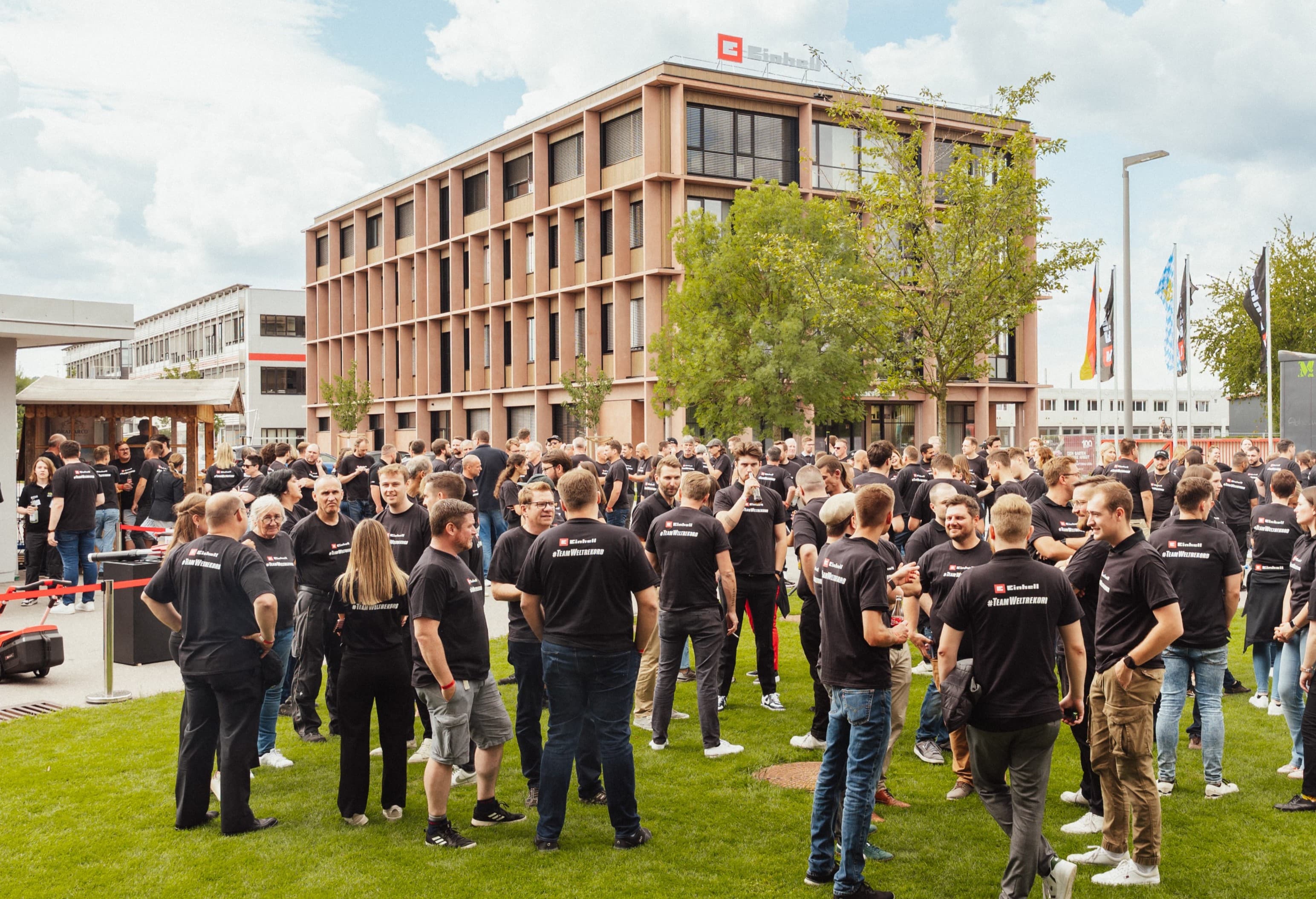 Zahlreiche Menschen in schwarzen Einhell-Shirts mit der Aufschrift "#TeamWeltrekord" stehen auf dem Firmengelände.
