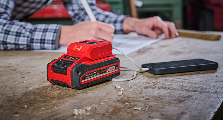 jemand nutzt den Einhell Akku-USB-Adapter als Powerbank für ein Smartphone