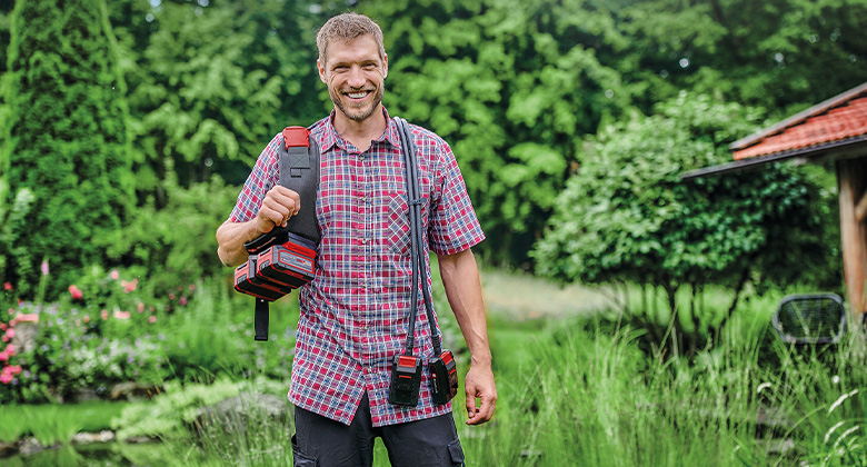 ein Mann mit dem Einhell Akku-Gürtel, zu sehen sind die beiden Akku-Dummys, die über die Schulter hängen