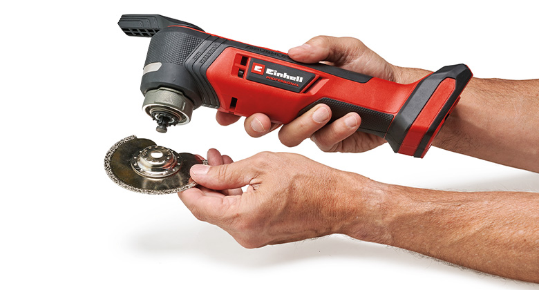Hands hold a Einhell multi-tool and prepare to attach a round cutting disc.