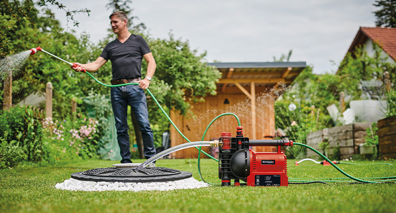 Ein Mann beim Pflanzengießen. Das benötigte Wasser wird durch eine Gartenpumpe aus einer Zisterne gepumpt.