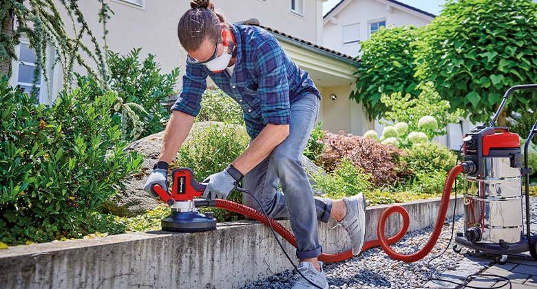 man using a wall and concrete grinder and a wet / dry vacuum cleaner