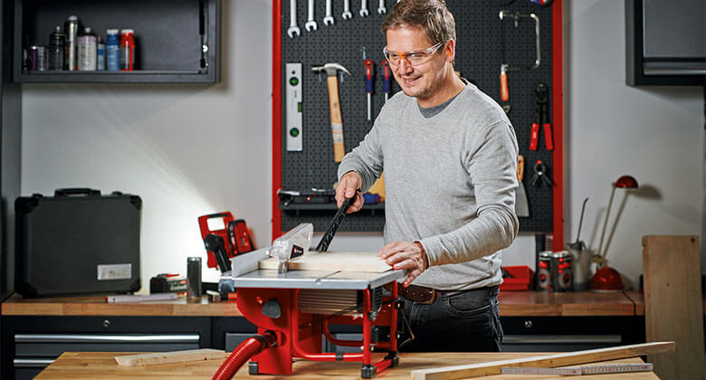 man using a table saw in a workshop