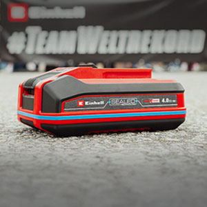 Eine Einhell SEALED Power X-Change 4,0 Ah Batterie liegt auf Asphalt.