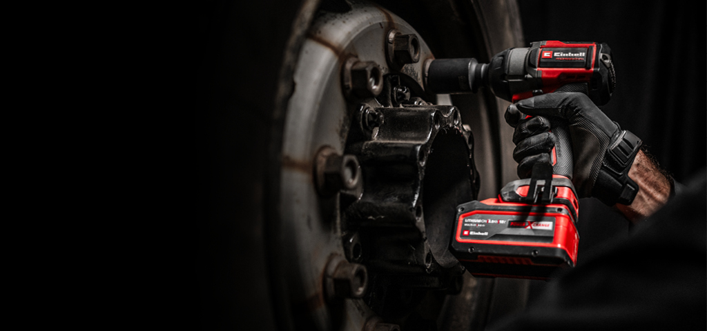 Close-up of a red cordless impact wrench being used on a wheel