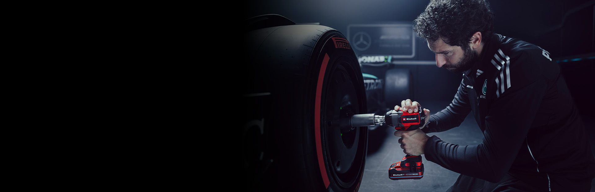 Der Banner zeigt eine Person, die mit einem rot-schwarzen Einhell-Akkuschlagschrauber an dem Rad eines Rennwagens in einer Werkstatt arbeitet.