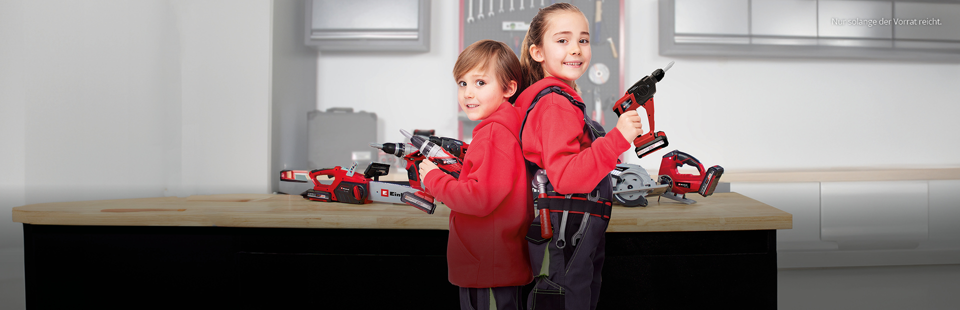 Aufnahme von zwei Kindern in Arbeitskleidung mit Spielzeugwerkzeugen in den Händen.
