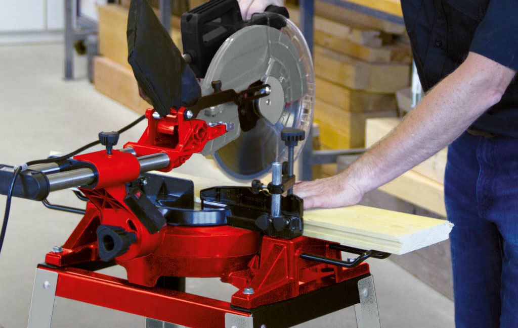 A person is cutting a wooden board with a Einhell mitre saw.